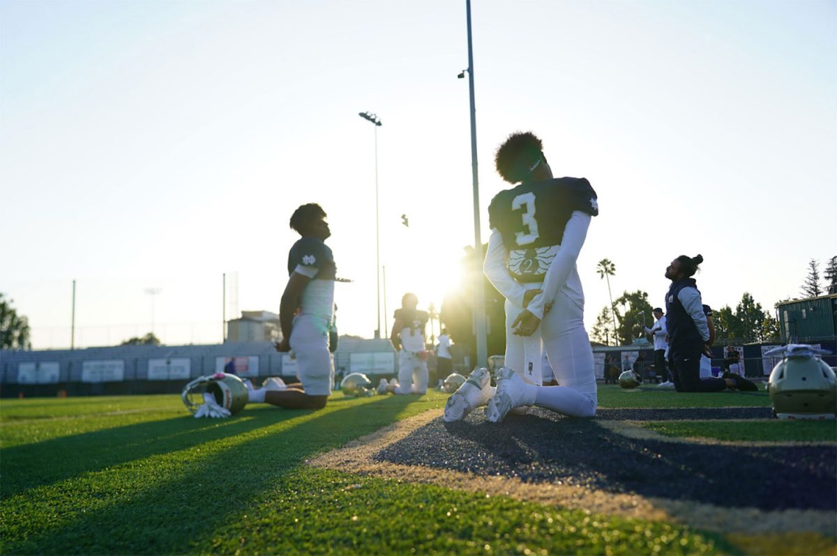 Notre Dame wide receivers Lloyd Weaver ’26, and Tre Fernandez III ‘25, are in the end zone stretching with Head Coach Yabu before the game against Westlake High School. The Knights won the match up with a score of 42-10.
