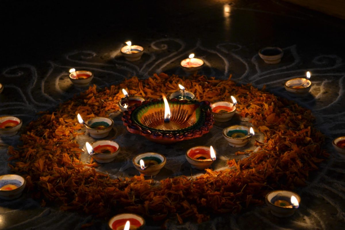 Diyas (clay lamps) are lit on the ground, surrounded by dried marigolds with chalk patterns imitating the sun.