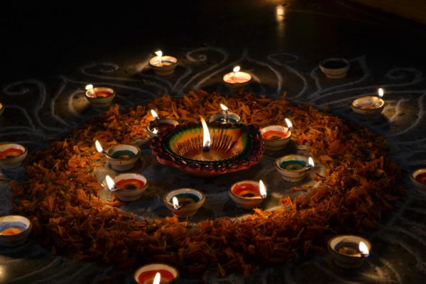 Diyas (clay lamps) are lit on the ground, surrounded by dried marigolds with chalk patterns imitating the sun.